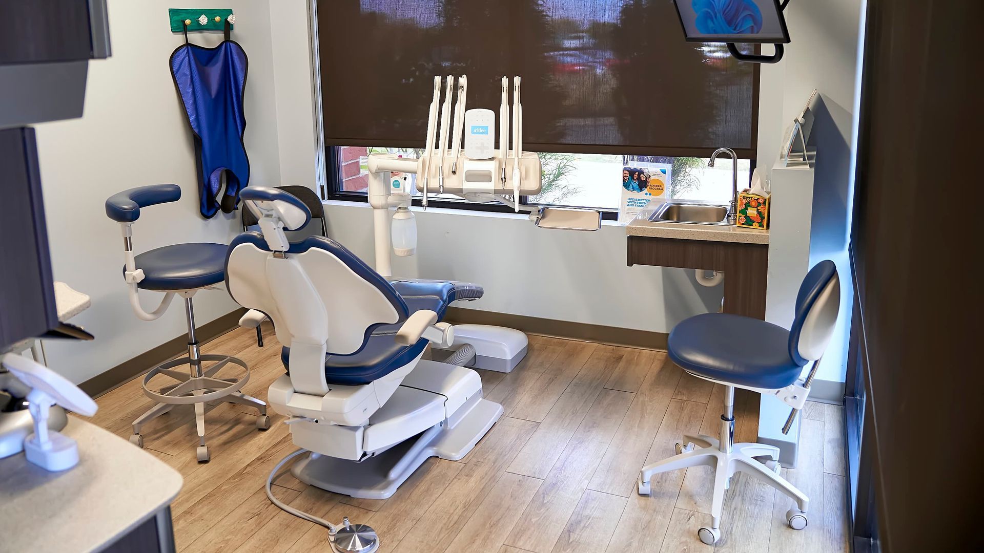 Dental operatory room with teal chair, instruments, and window.