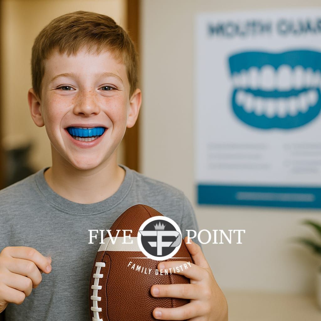 Boy wearing a blue mouthguard smiles, holding a football. Sign for mouthguards in the background.