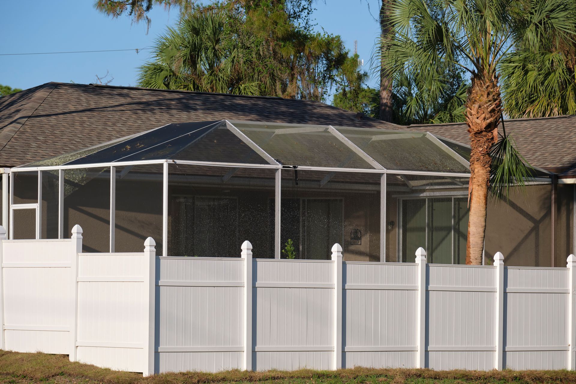 A house with a screened in porch and a white fence