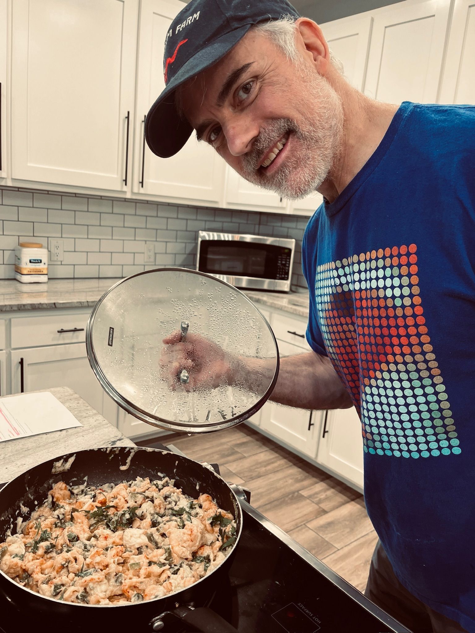 A man in a blue shirt is cooking food in a frying pan.