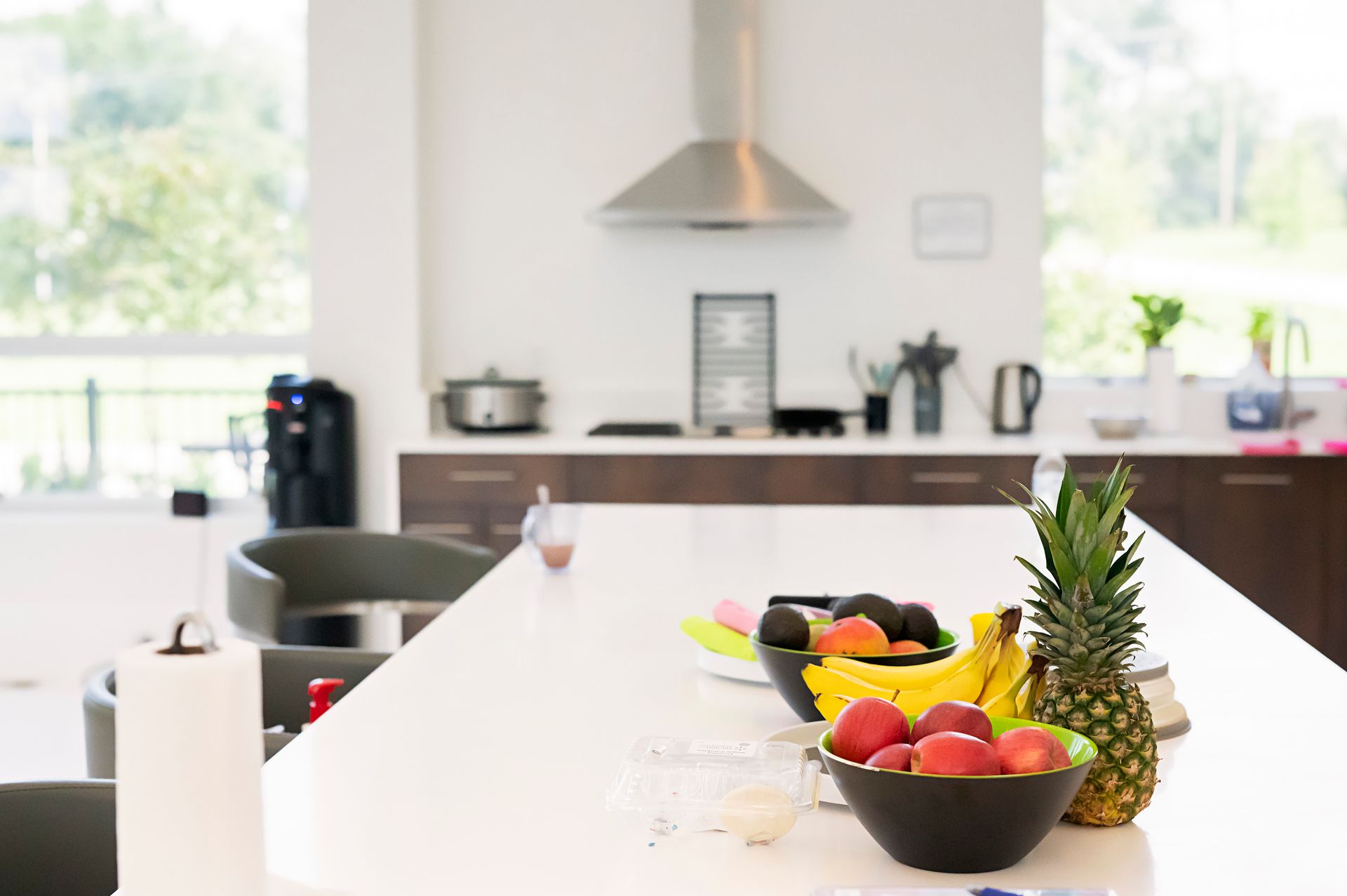A kitchen with a bowl of fruit and a pineapple on the counter.