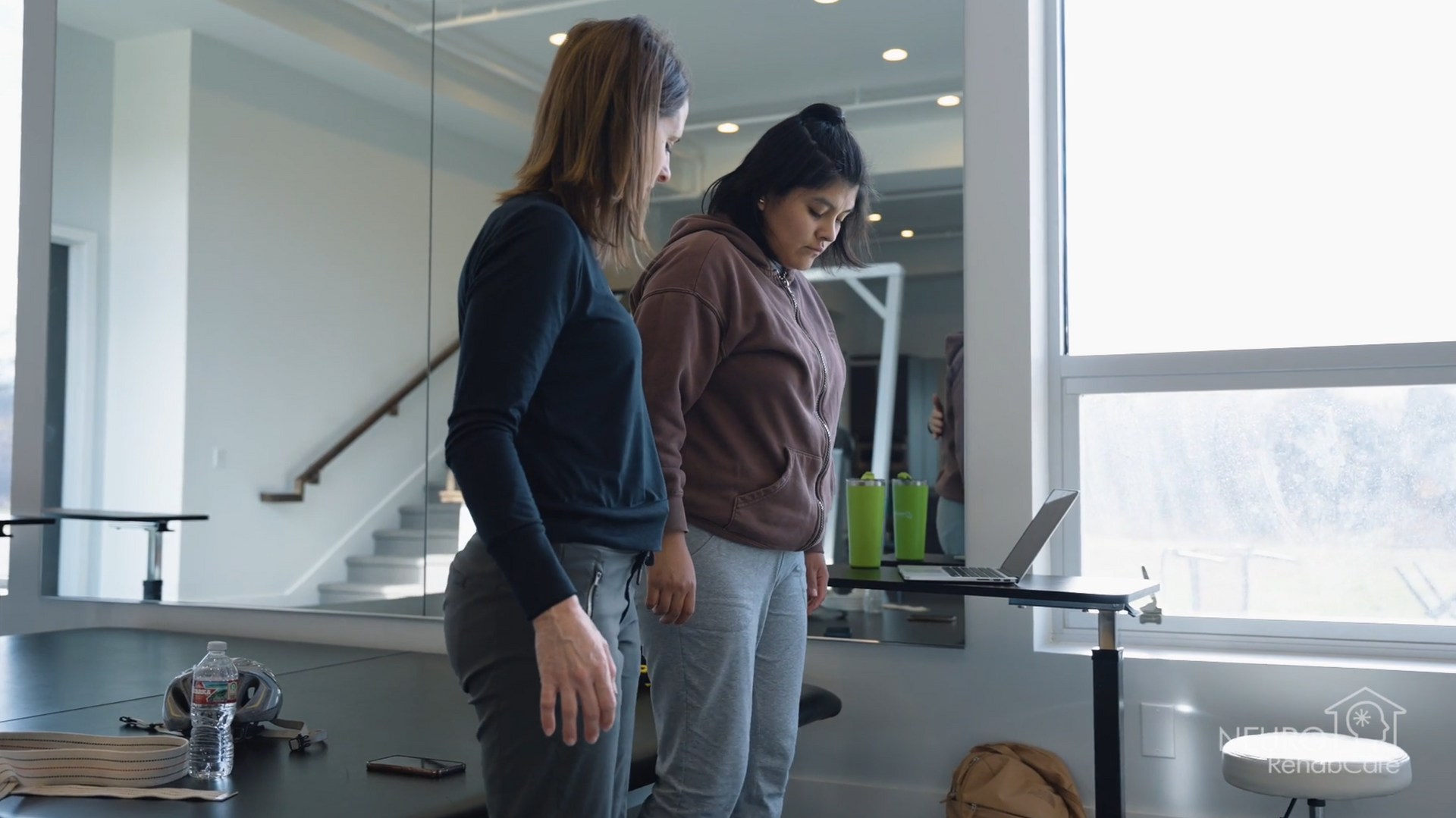 Two women are standing next to each other in a room looking at a laptop.