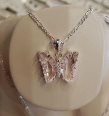 Un primer plano de un collar con un colgante de mariposa en un maniquí.
