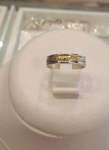 Un anillo de plata y oro reposa sobre una pantalla blanca.