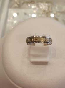 Un anillo de plata y oro reposa sobre una vitrina blanca.