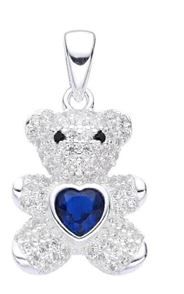 Un colgante de osito de peluche de plata con un corazón azul en sus patas.