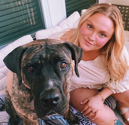 Sidne Hecht cuddles a large brindle dog on a porch.