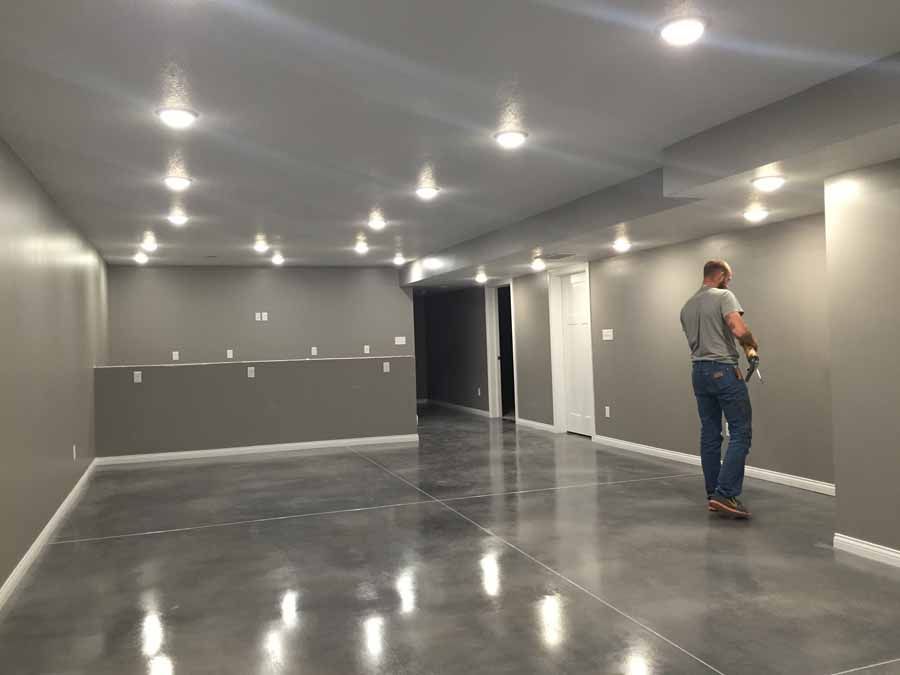 A man is standing in a large empty room with a concrete floor.
