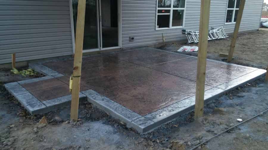 A concrete patio is being built in front of a house.