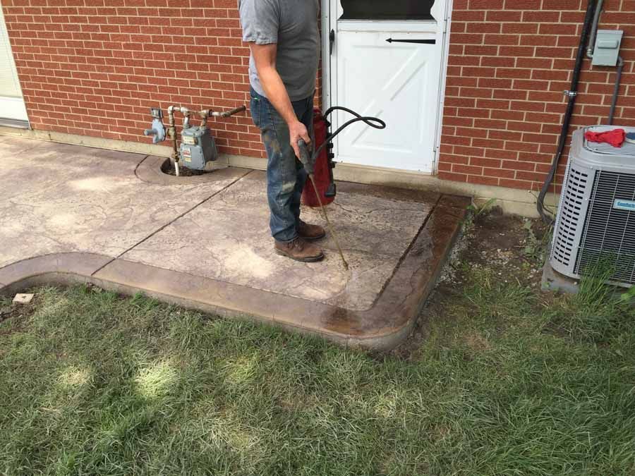 A man is standing in front of a brick building holding a fire extinguisher.