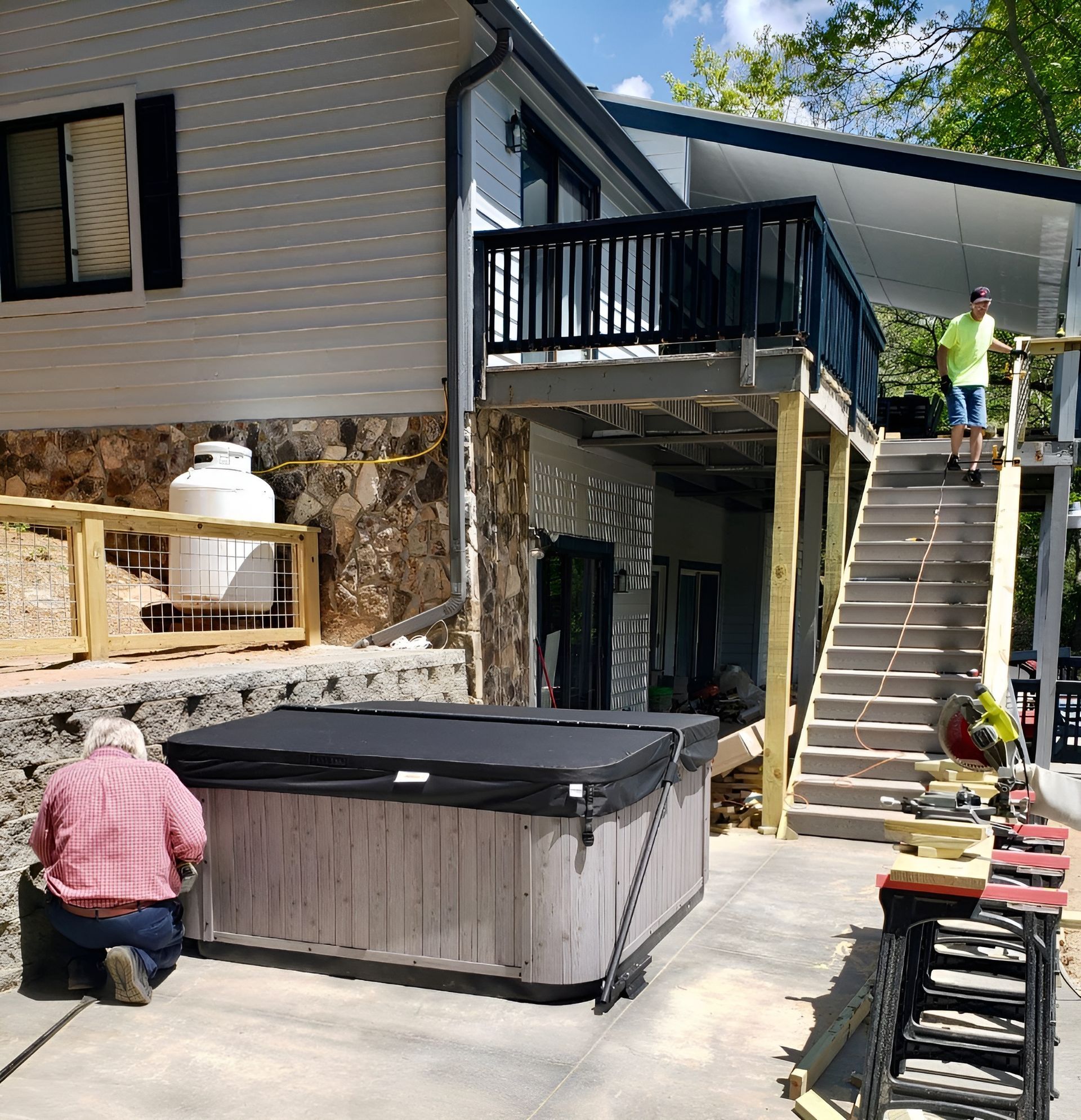A man is kneeling next to a hot tub in front of a house