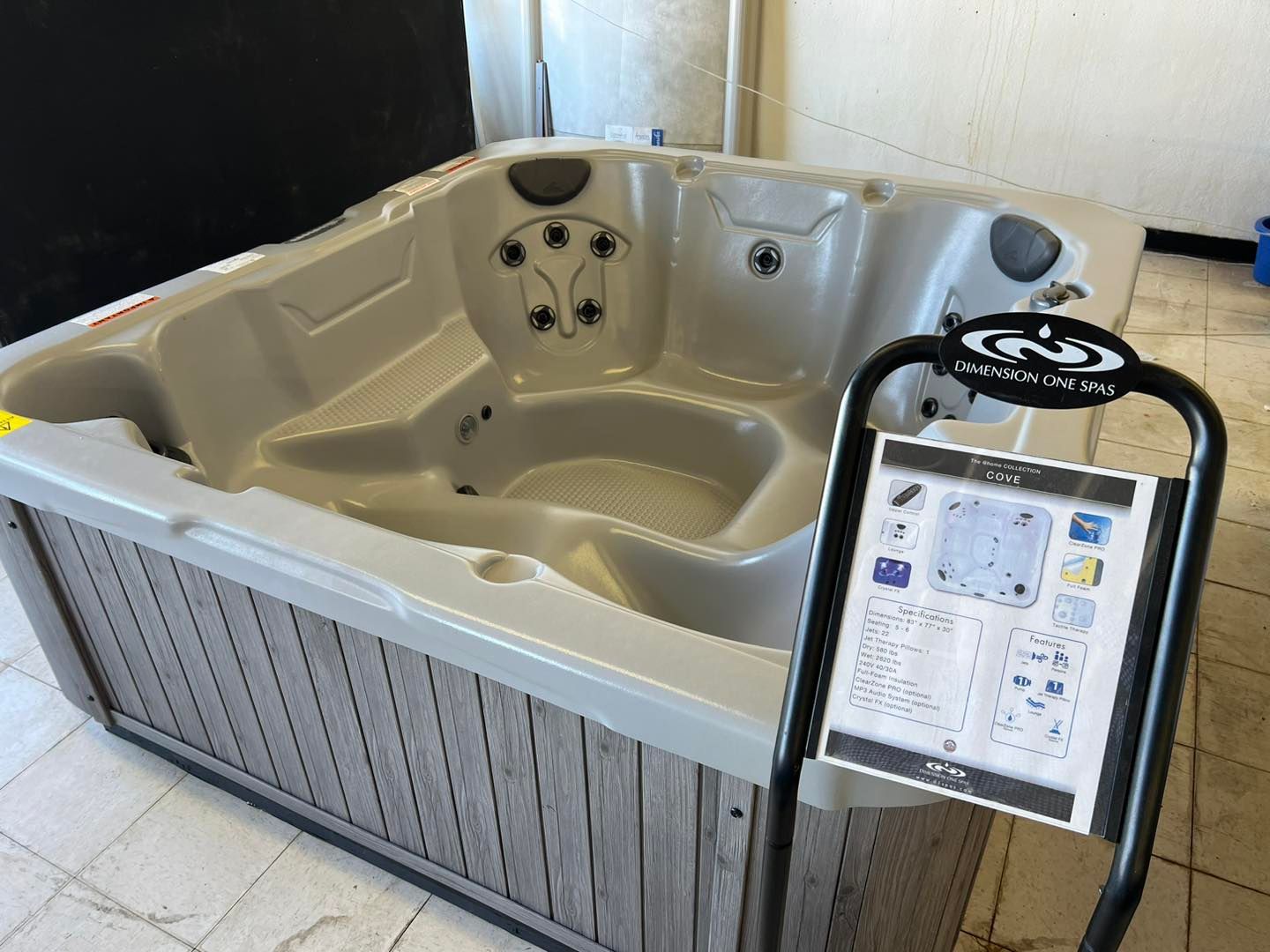 A hot tub is sitting on a tiled floor next to a sign.