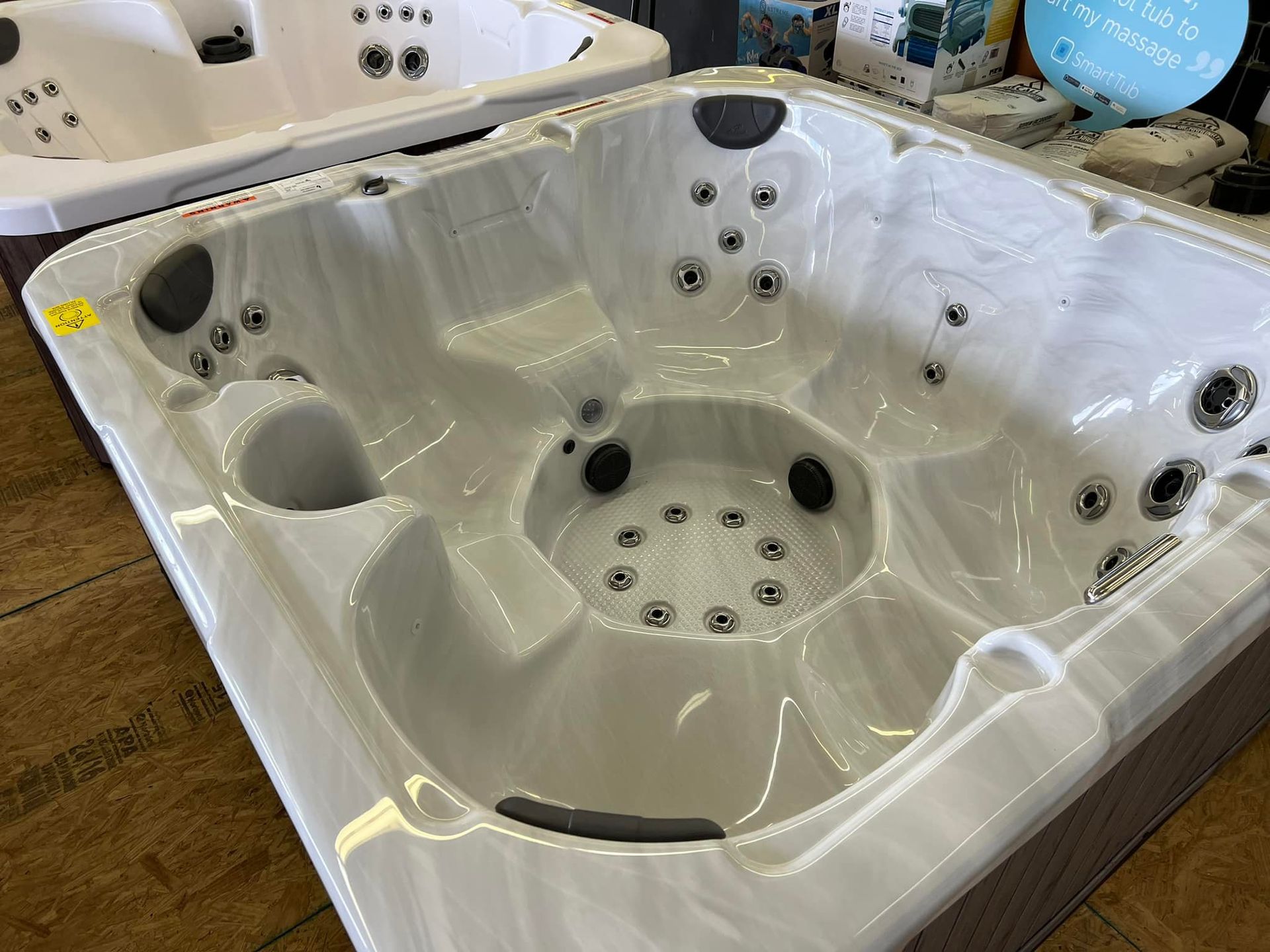 A white hot tub is sitting on top of a wooden floor.