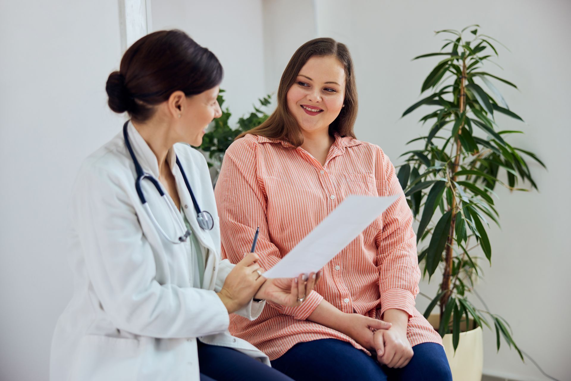 Doctor discussing paperwork with a smiling patient in a bright clinic room