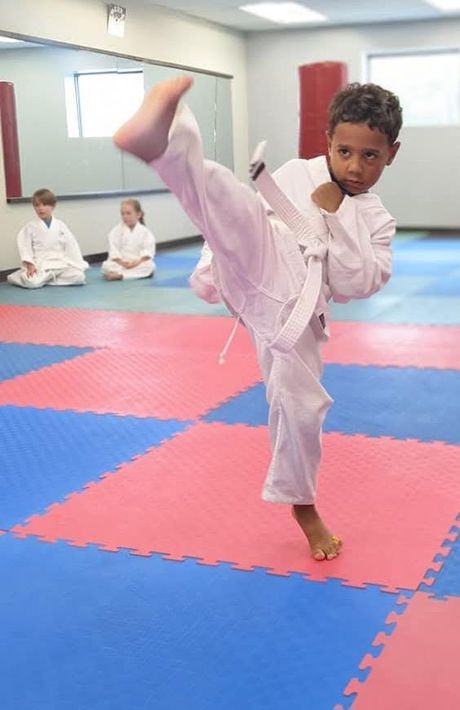 Youth martial arts students practicing kicking drills