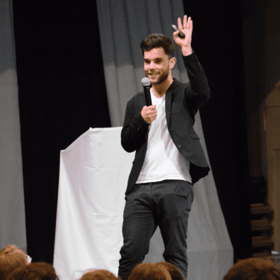 A man in a suit is holding a microphone and waving