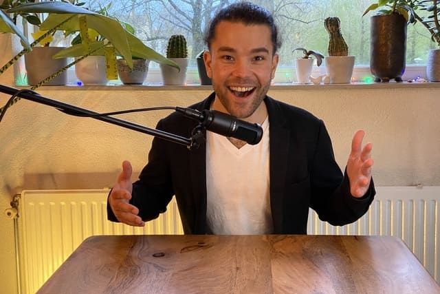 A man is sitting at a table in front of a microphone.