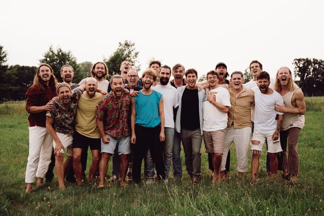 A large group of men are posing for a picture in a grassy field.