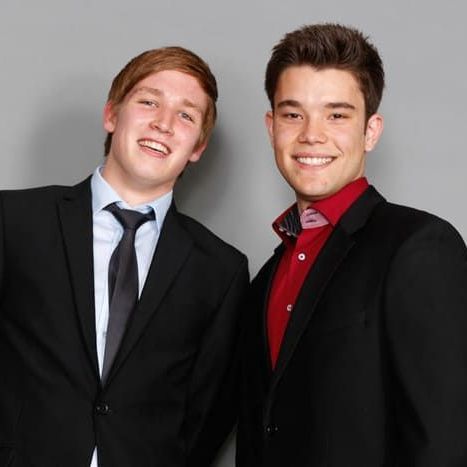 Two men in suits and ties are posing for a picture