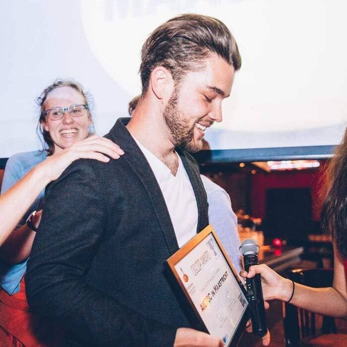 A man is holding a framed certificate and a microphone