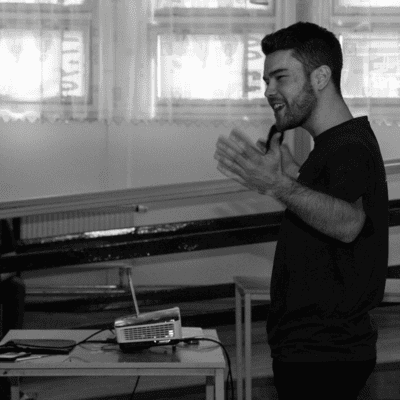 A man stands in front of a projector in a black and white photo