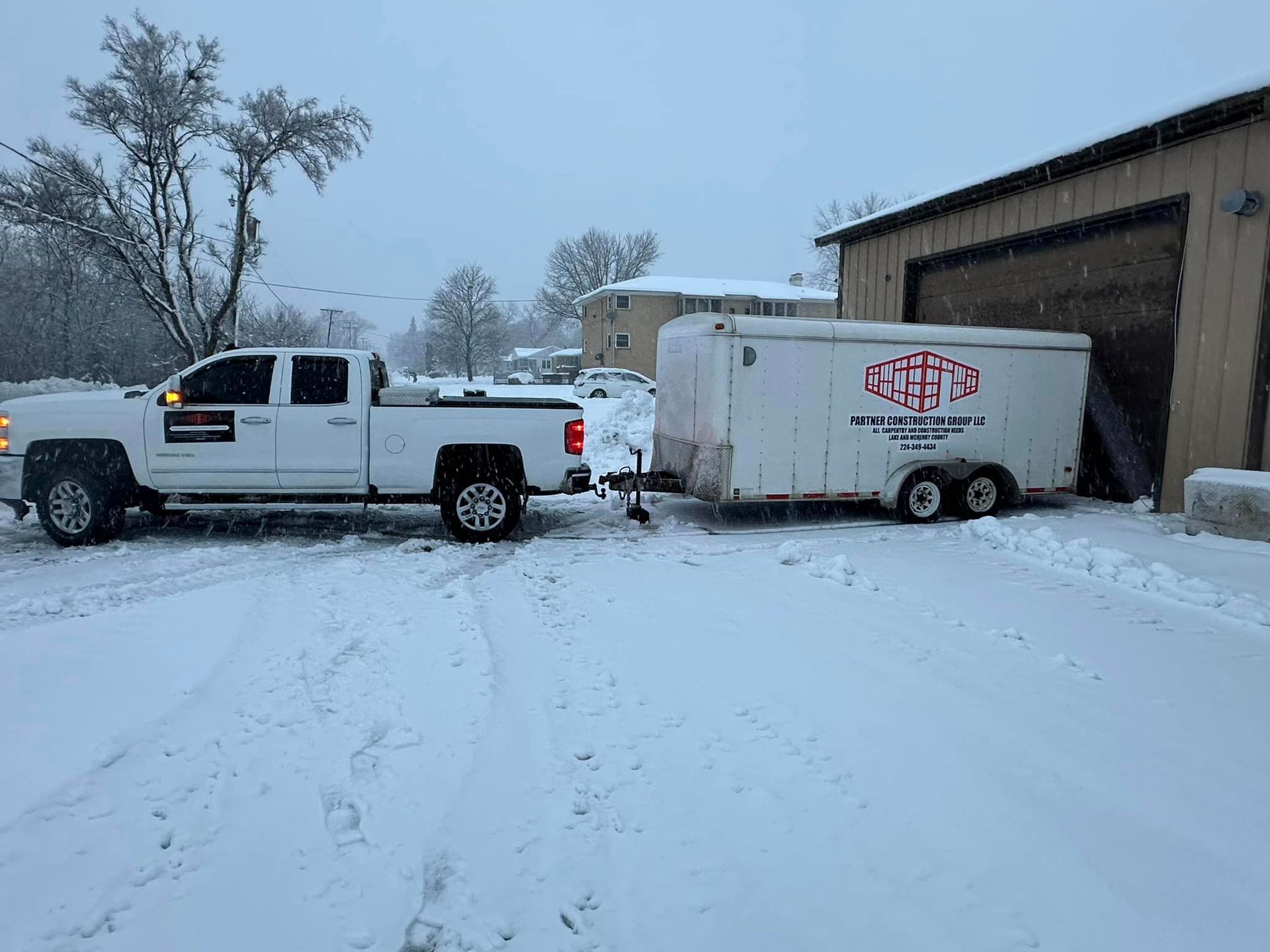 a white truck is pulling a trailer in the snow .