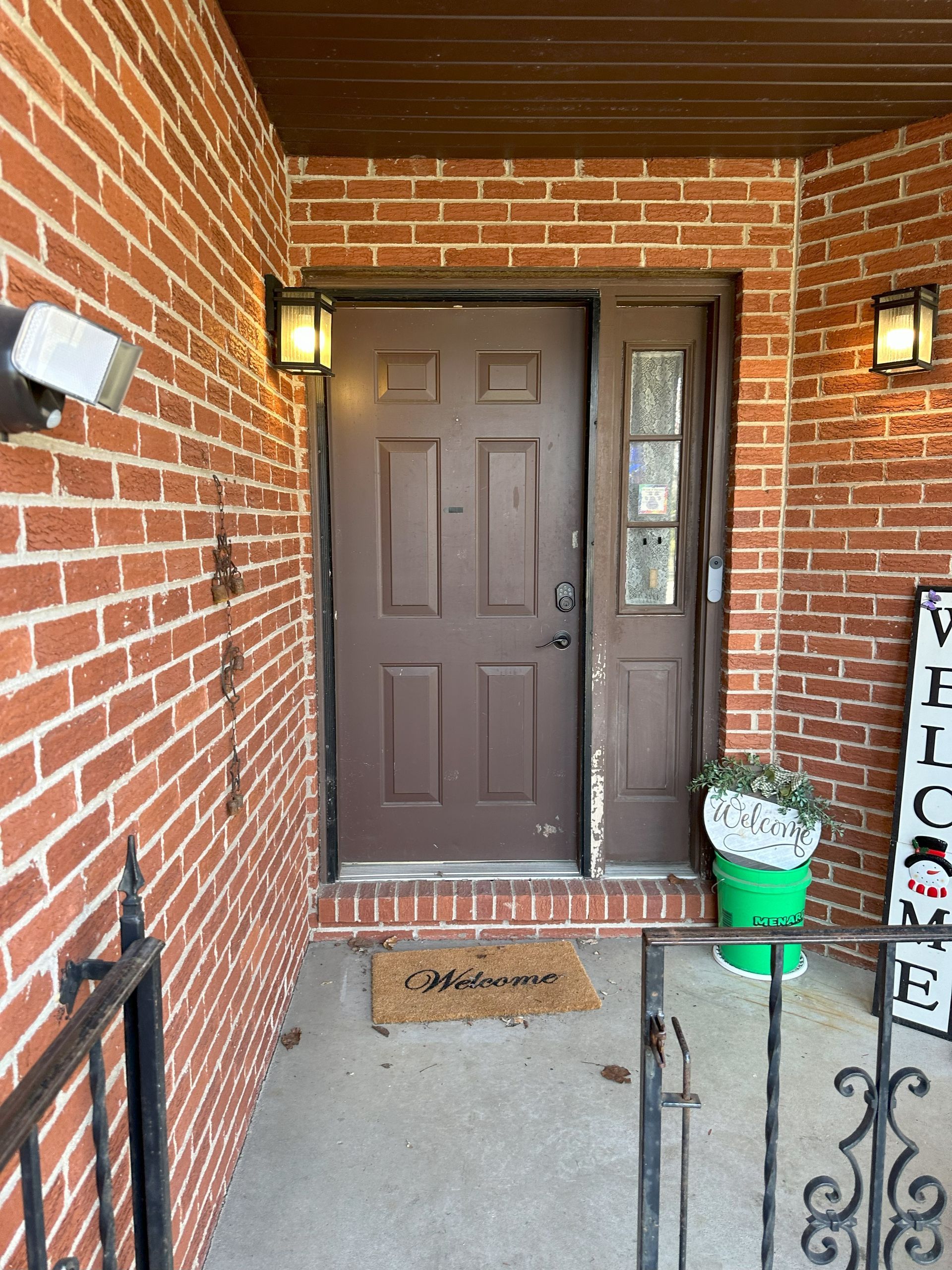a brick wall with a brown door and a welcome sign