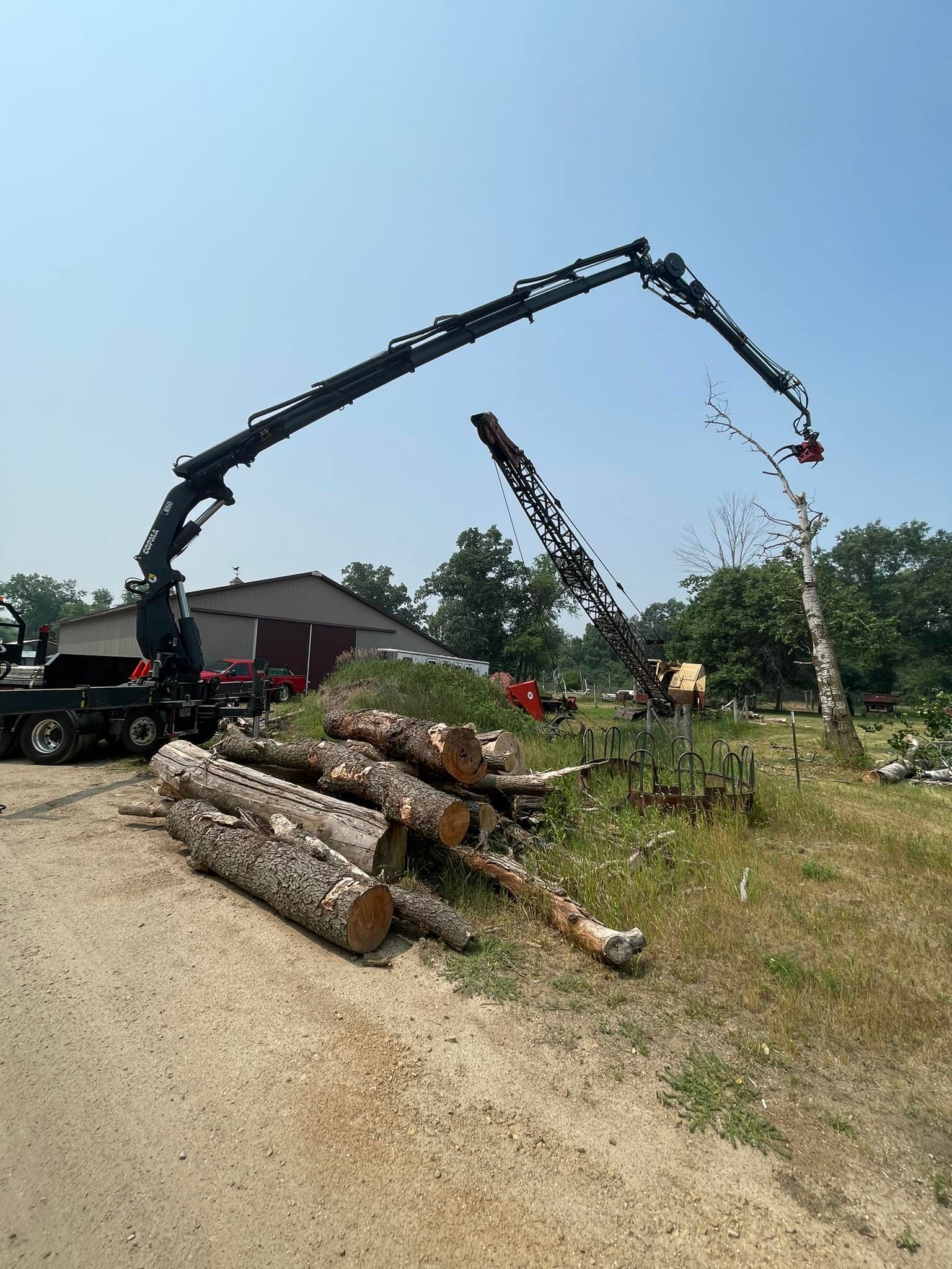A truck with a crane attached to it is carrying logs.