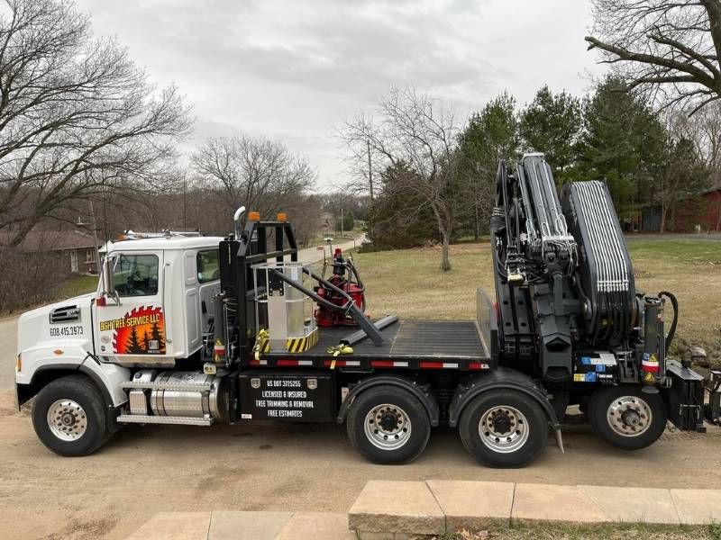 A semi truck with a crane on the back is parked in a driveway.