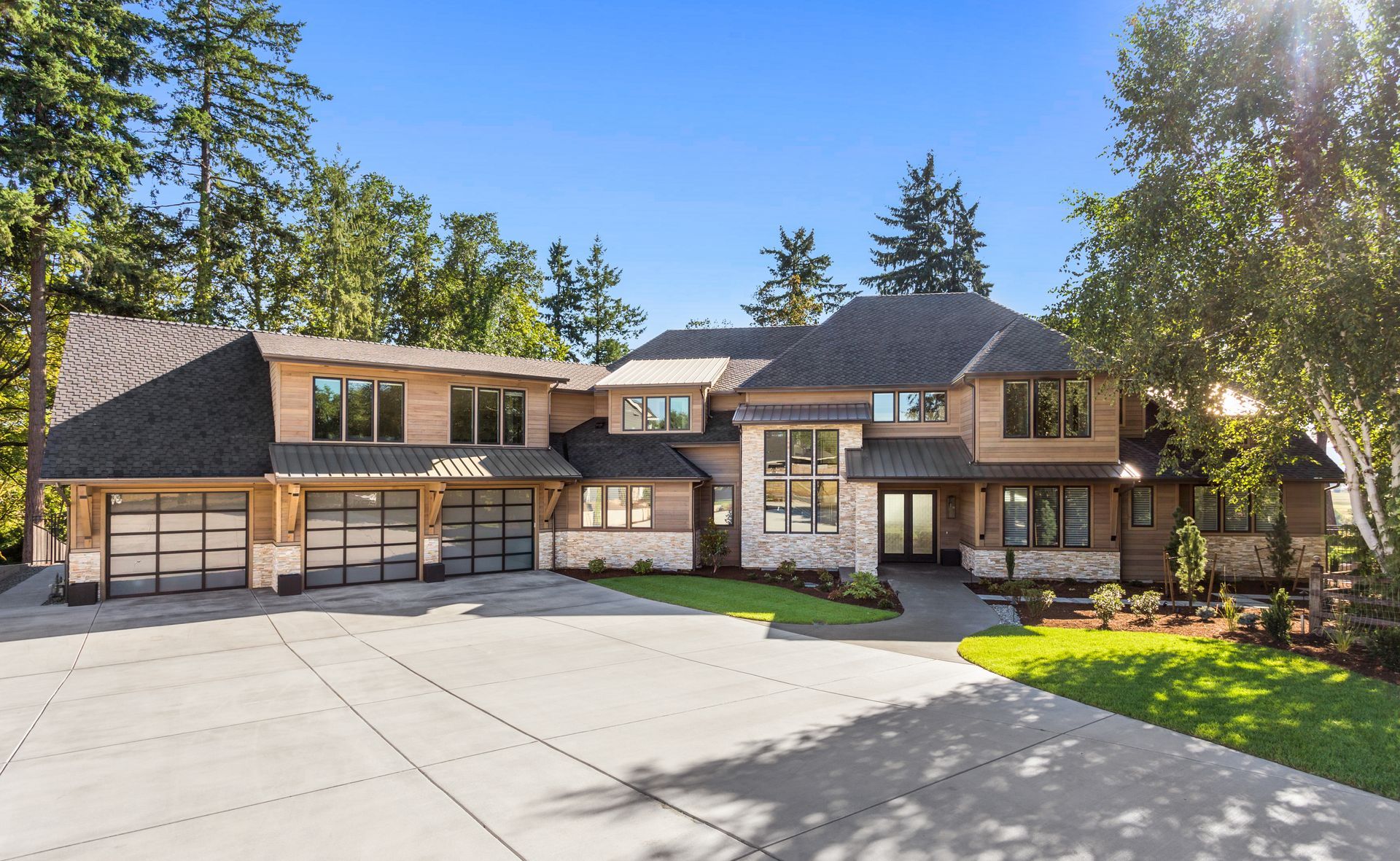 A large house with a concrete driveway in front of it surrounded by trees.