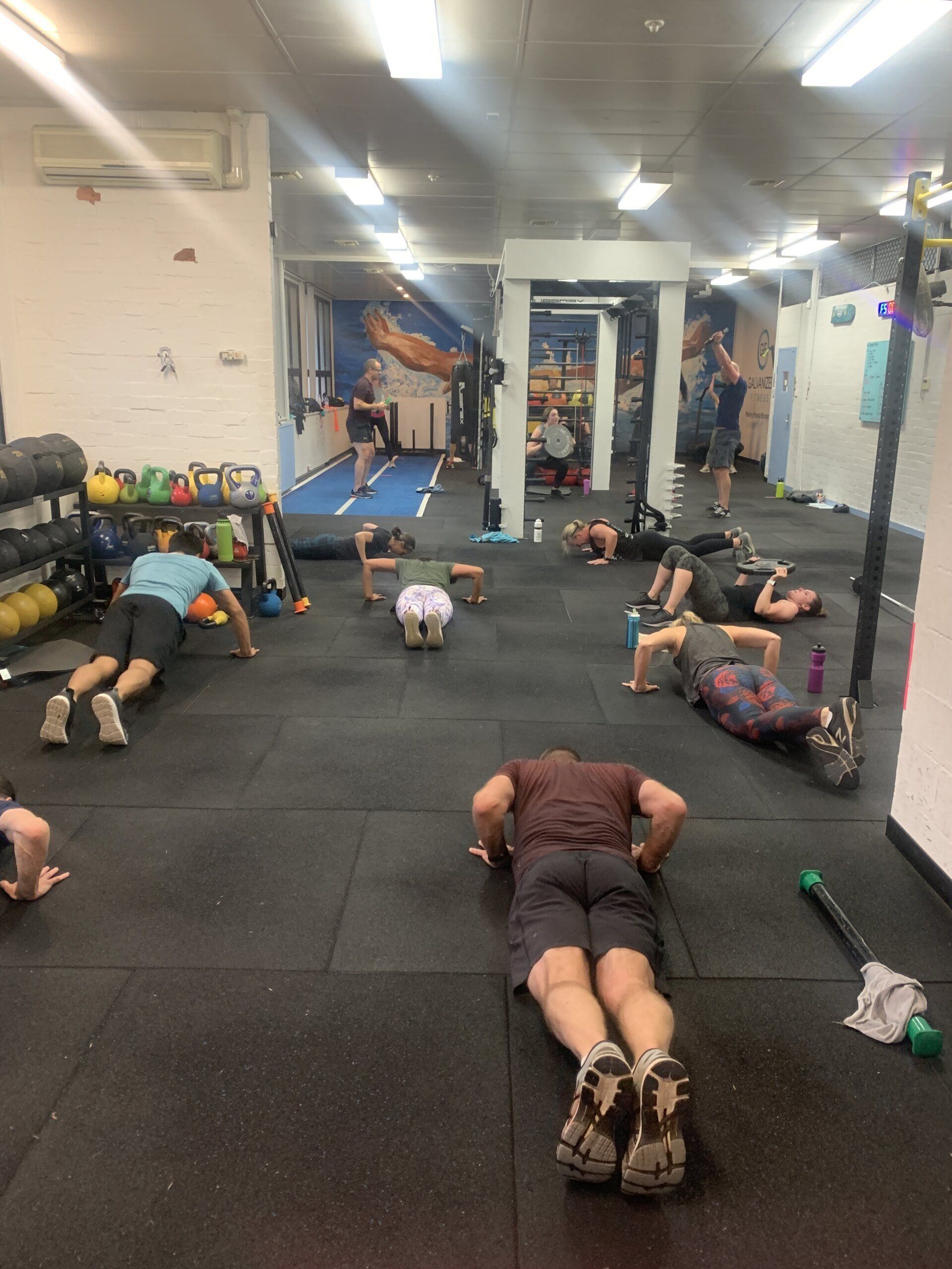A group of people are doing push ups in a gym.