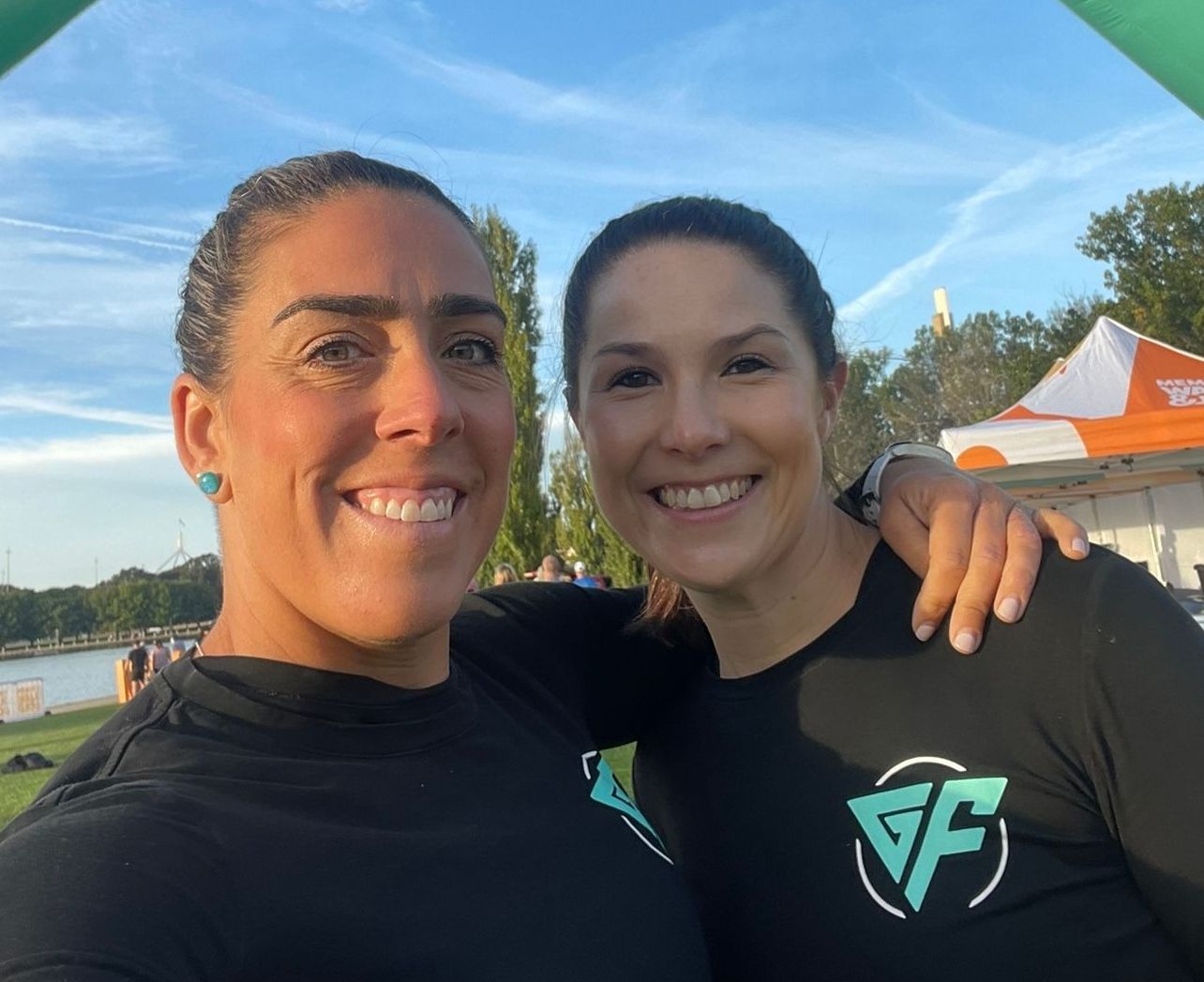 Two women are posing for a picture and one has the letter f on her shirt