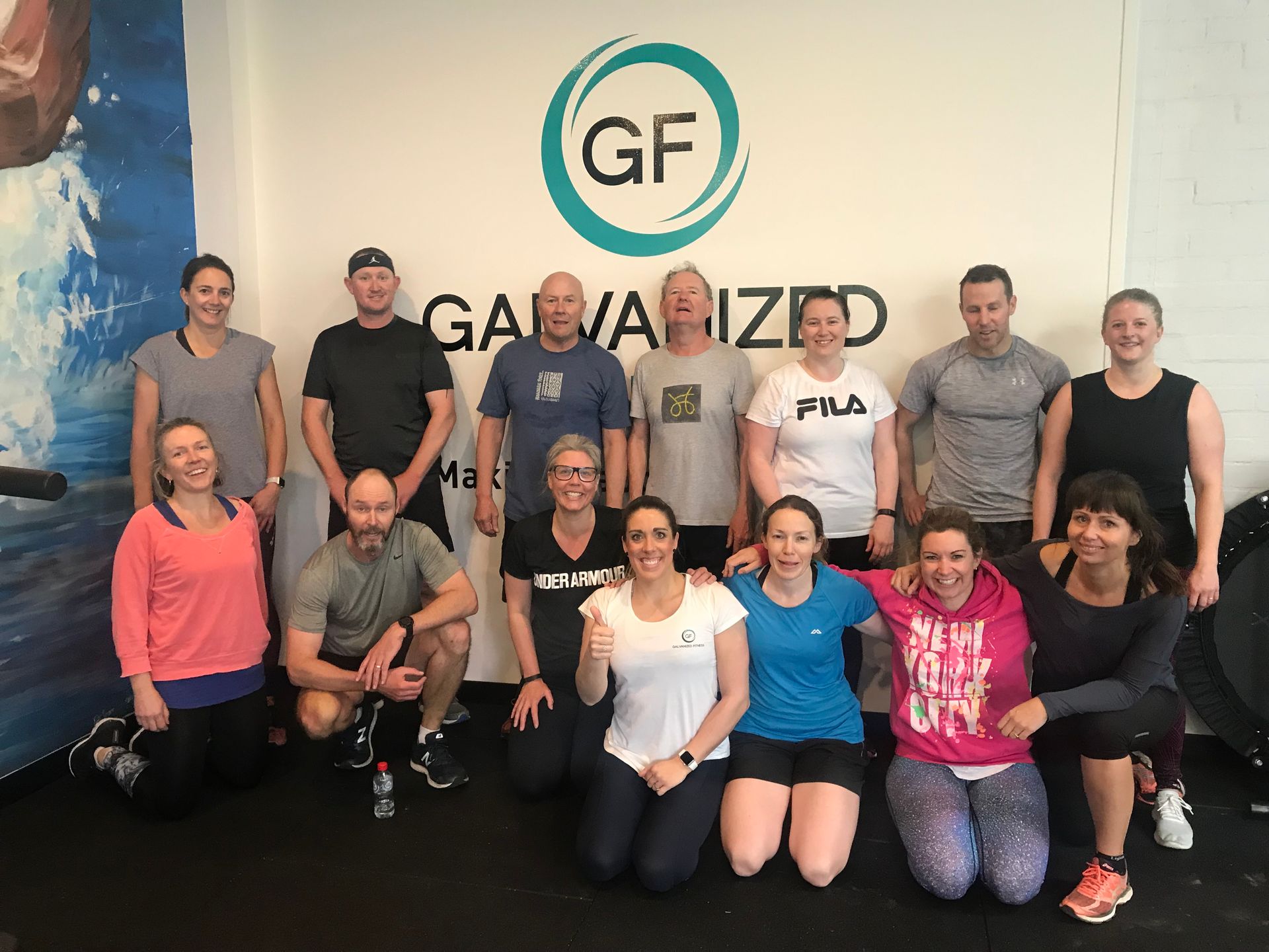 A group of people are posing for a picture in front of a sign that says galvanized.