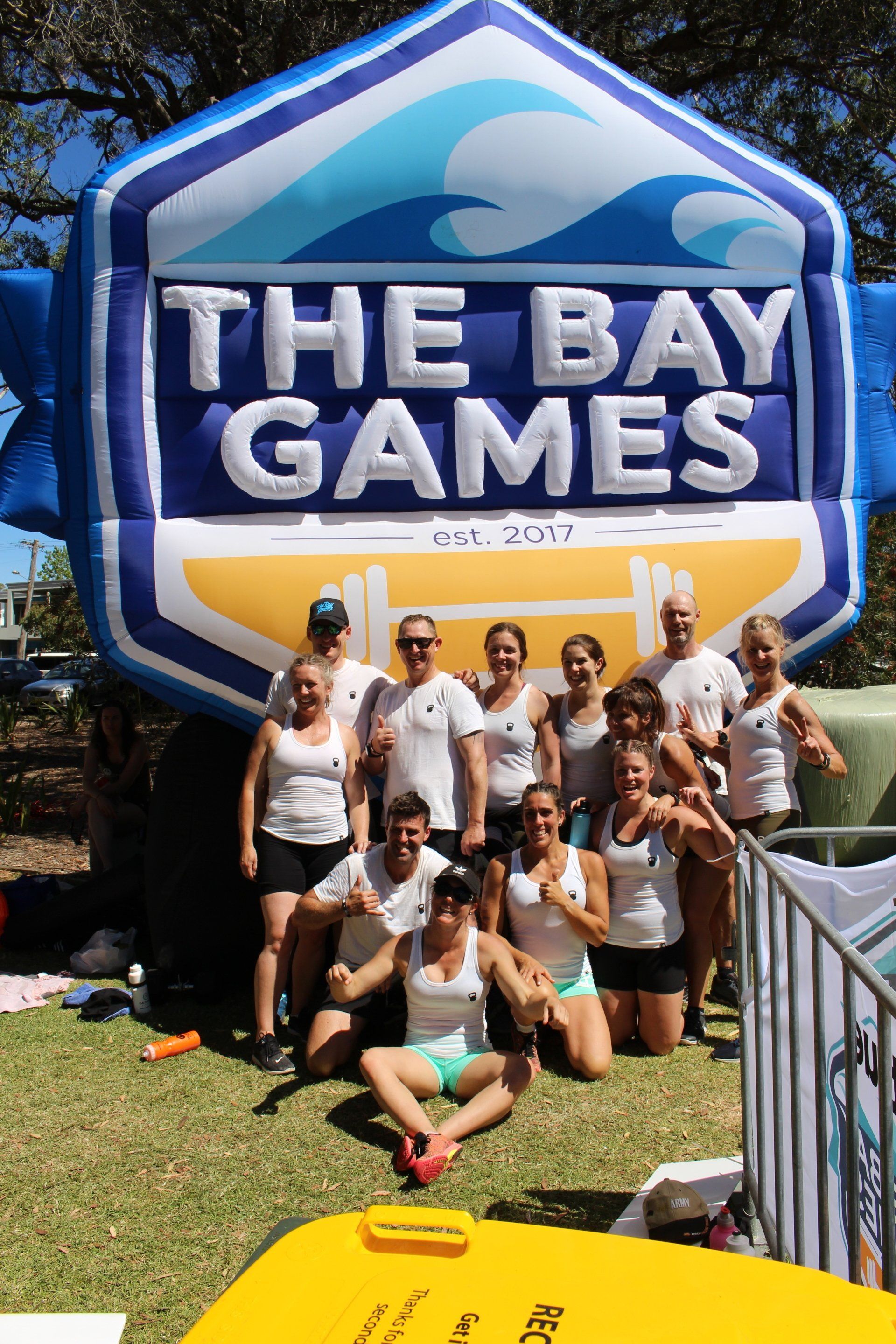 A group of people posing in front of a large inflatable sign that says the bay games