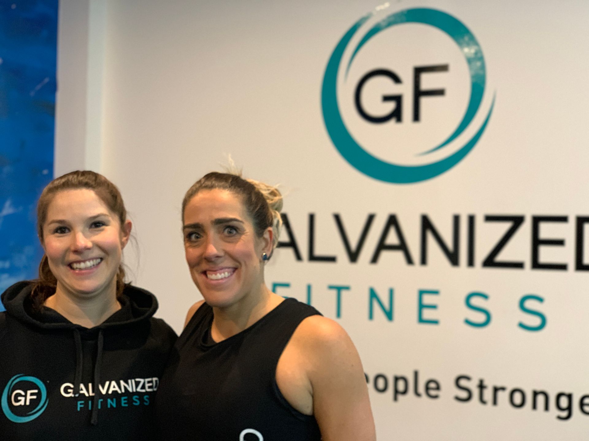 Two women are standing in front of a sign that says galvanized fitness