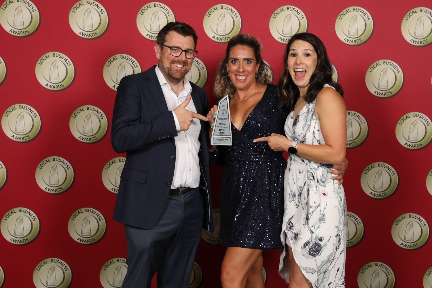 A group of people are posing for a picture in front of a red wall with circles on it.
