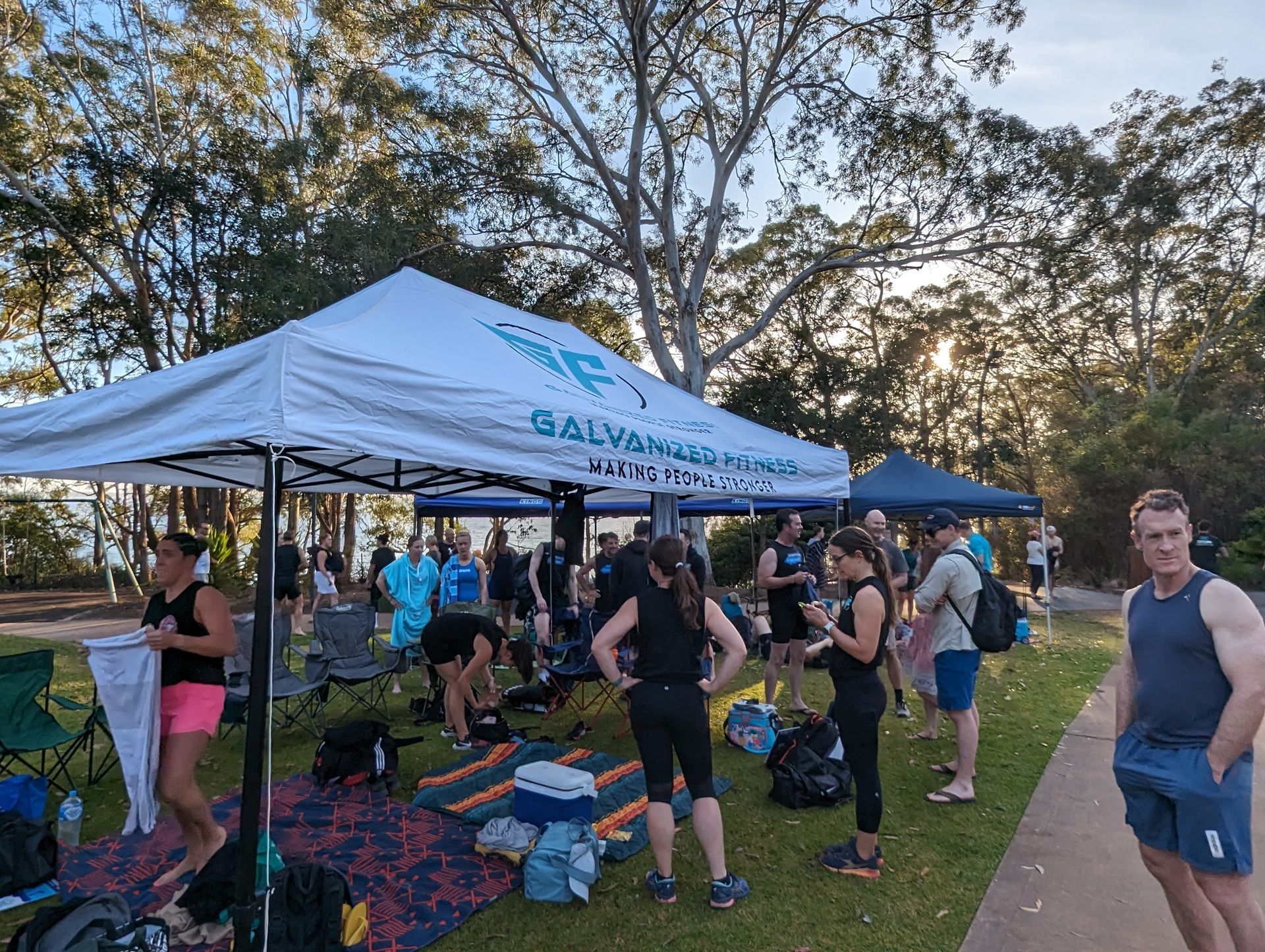 A group of people are standing under a tent in a park.