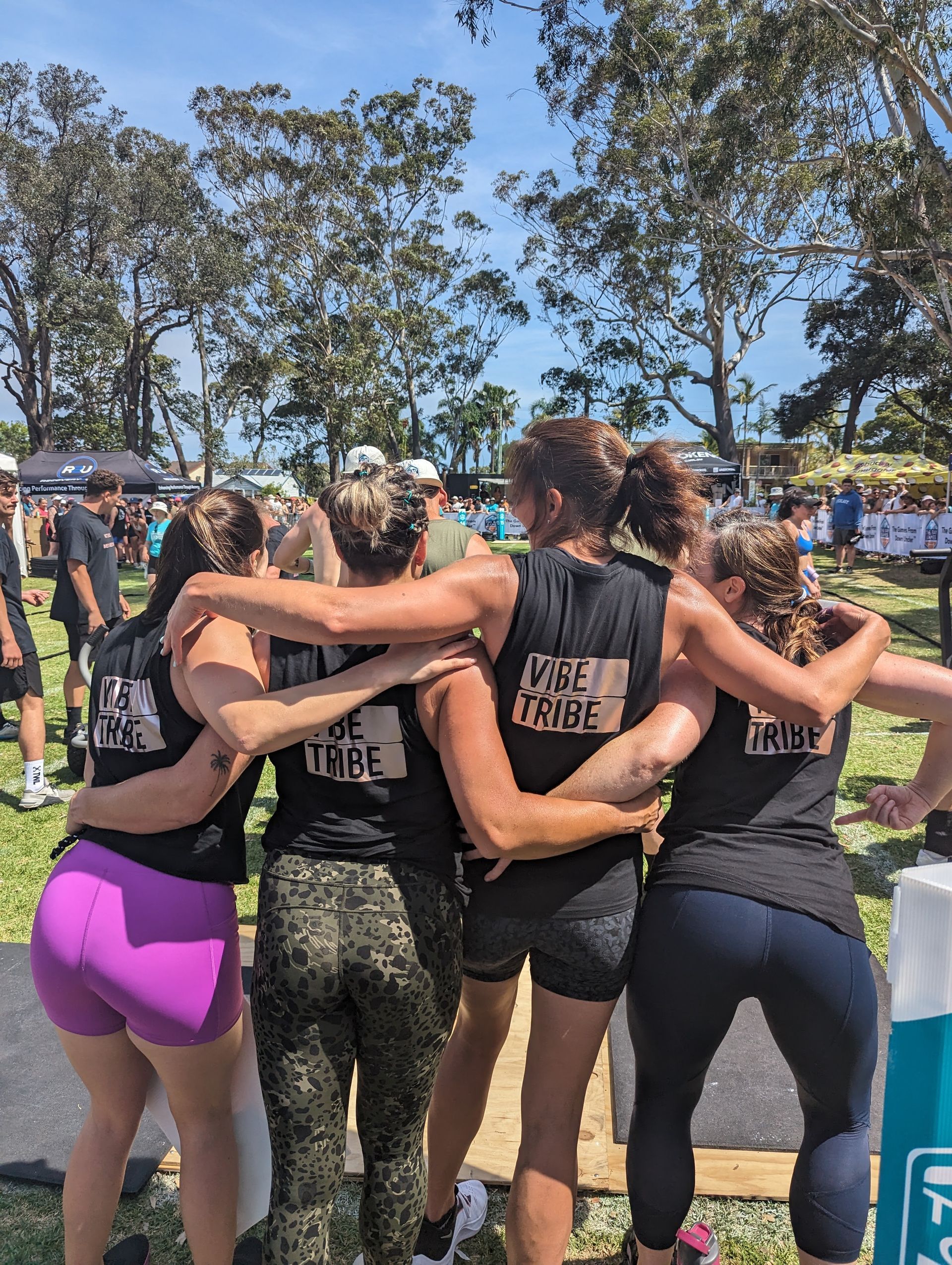 A group of women are hugging each other in a field.