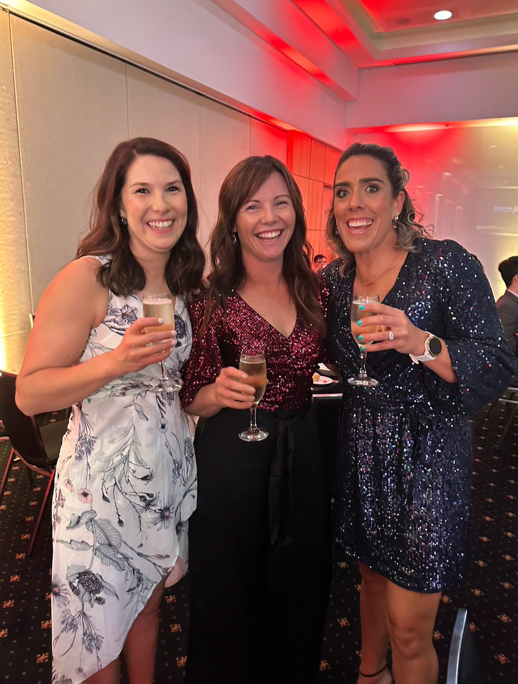 Three women are posing for a picture while holding champagne glasses.