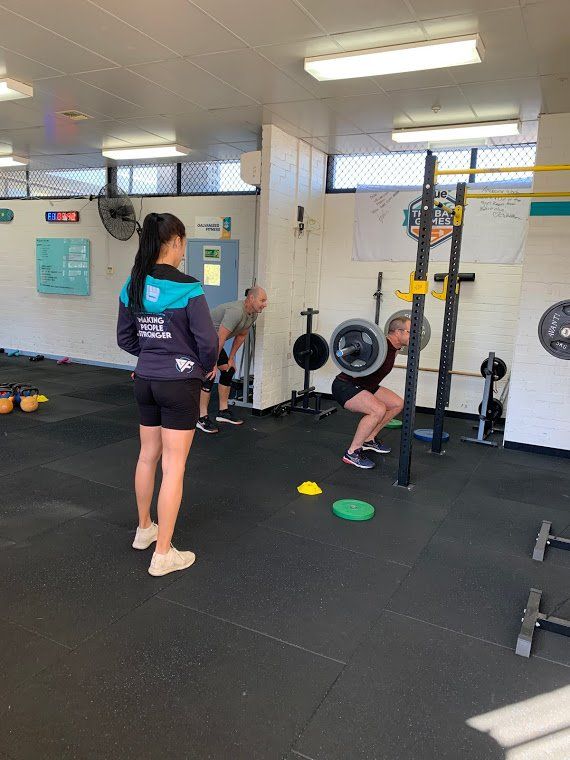 A group of people are doing squats in a gym.
