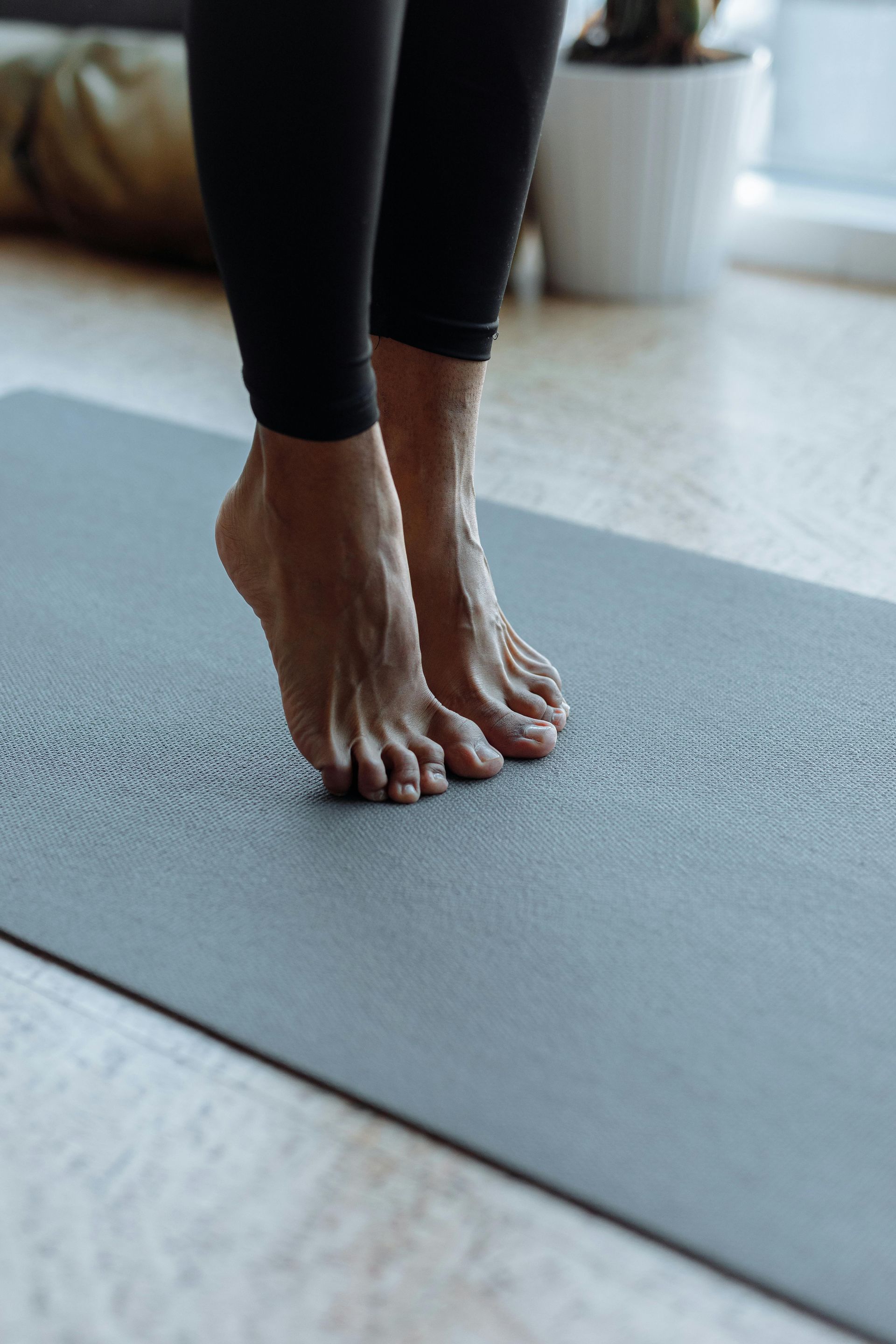 A person is standing on a yoga mat with their feet up.