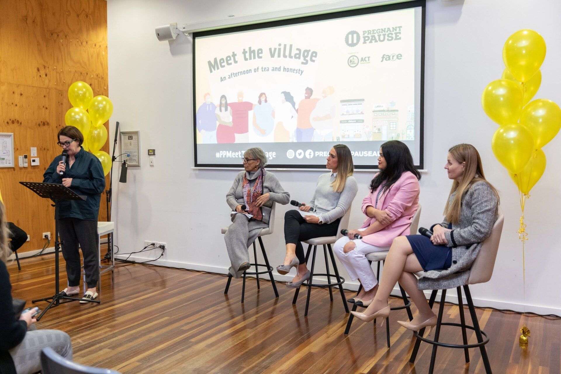 A group of women are sitting in chairs in front of a projector screen.