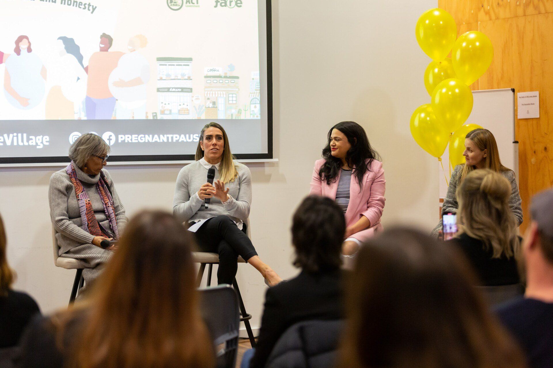A group of women are sitting in front of a projector screen.