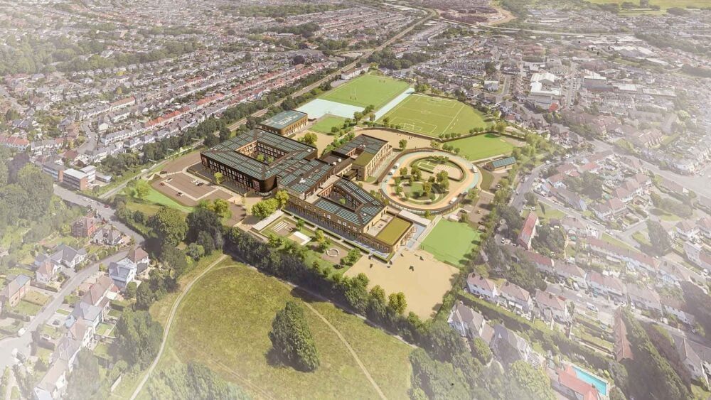 Aerial view of a modern school complex, featuring multiple buildings, sports fields, and a circular courtyard.