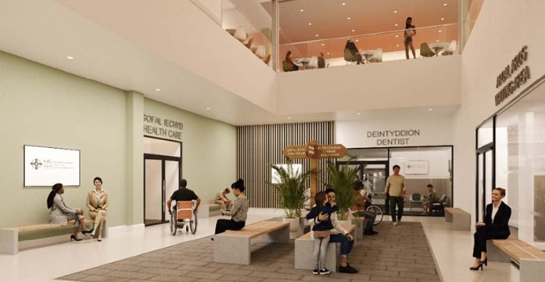 Interior of a modern healthcare facility, with patients waiting on benches, light walls, and two floors.