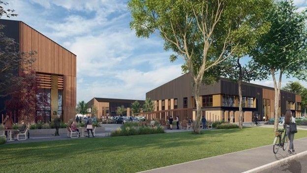 Buildings with wood paneling and black accents, people on benches and a cyclist on a path, outdoors.