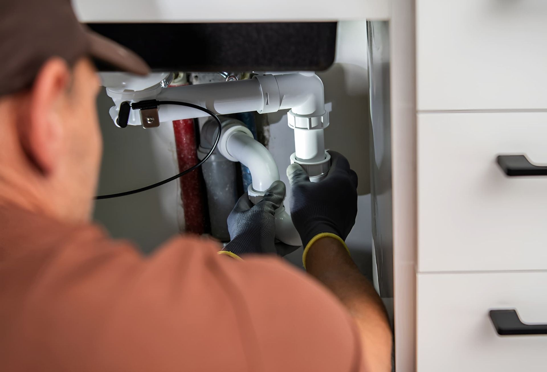 A Plumber Is Fixing A Sink In A Kitchen — GPS Plumbing, Drainage & Gasfitting In Dubbo, NSW