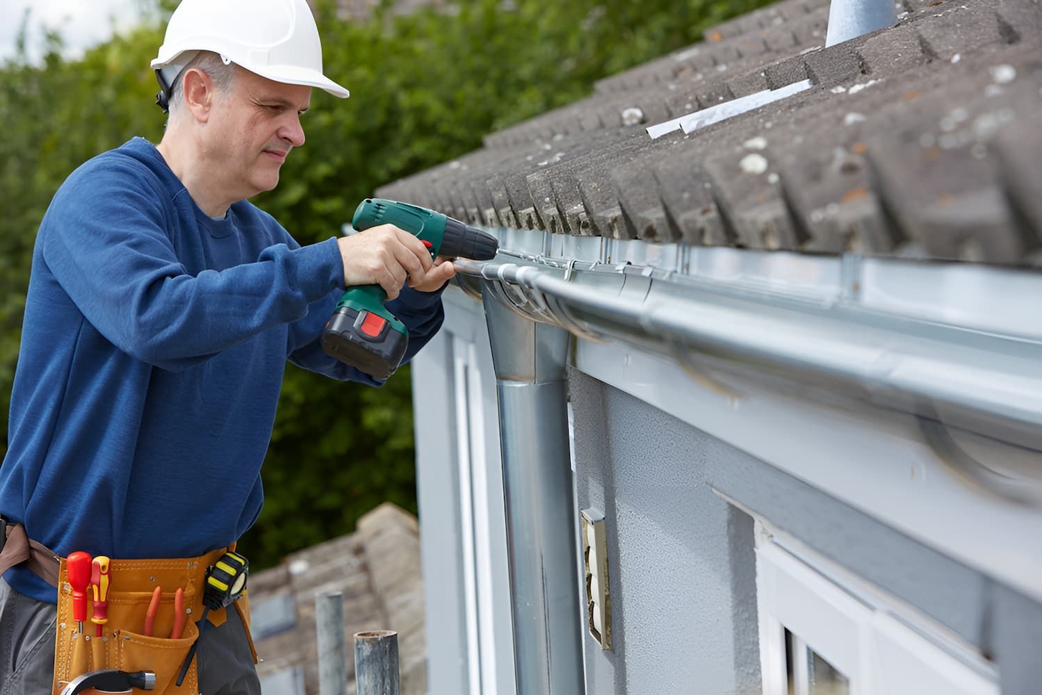 A Man Is Installing A Gutter On The Side Of A House — GPS Plumbing, Drainage & Gasfitting In Narromine, NSW
