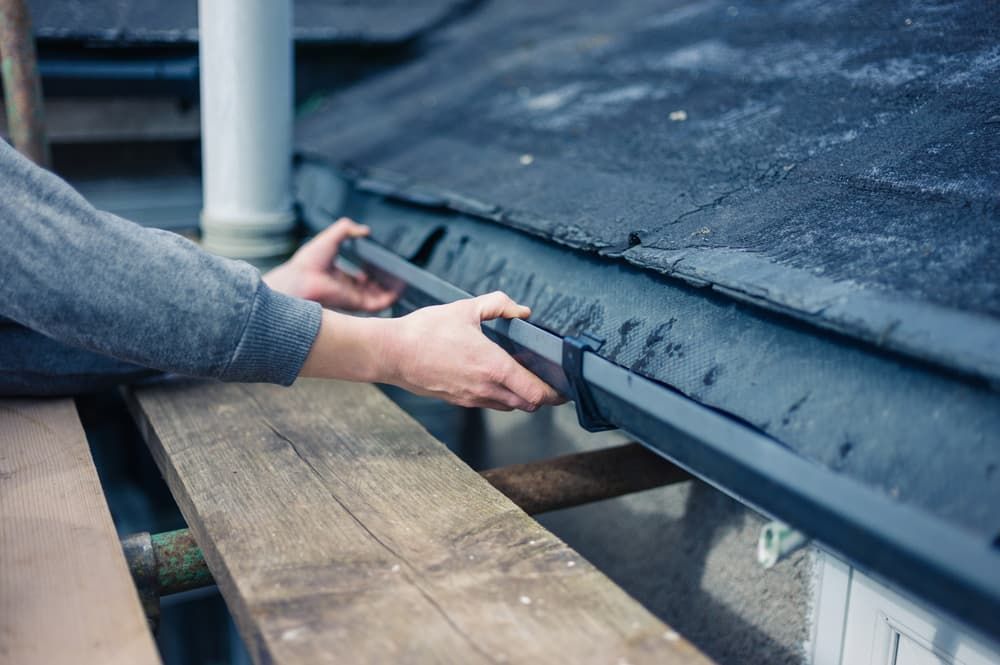 A Person Is Fixing A Gutter On A Roof — GPS Plumbing, Drainage & Gasfitting In Dubbo, NSW