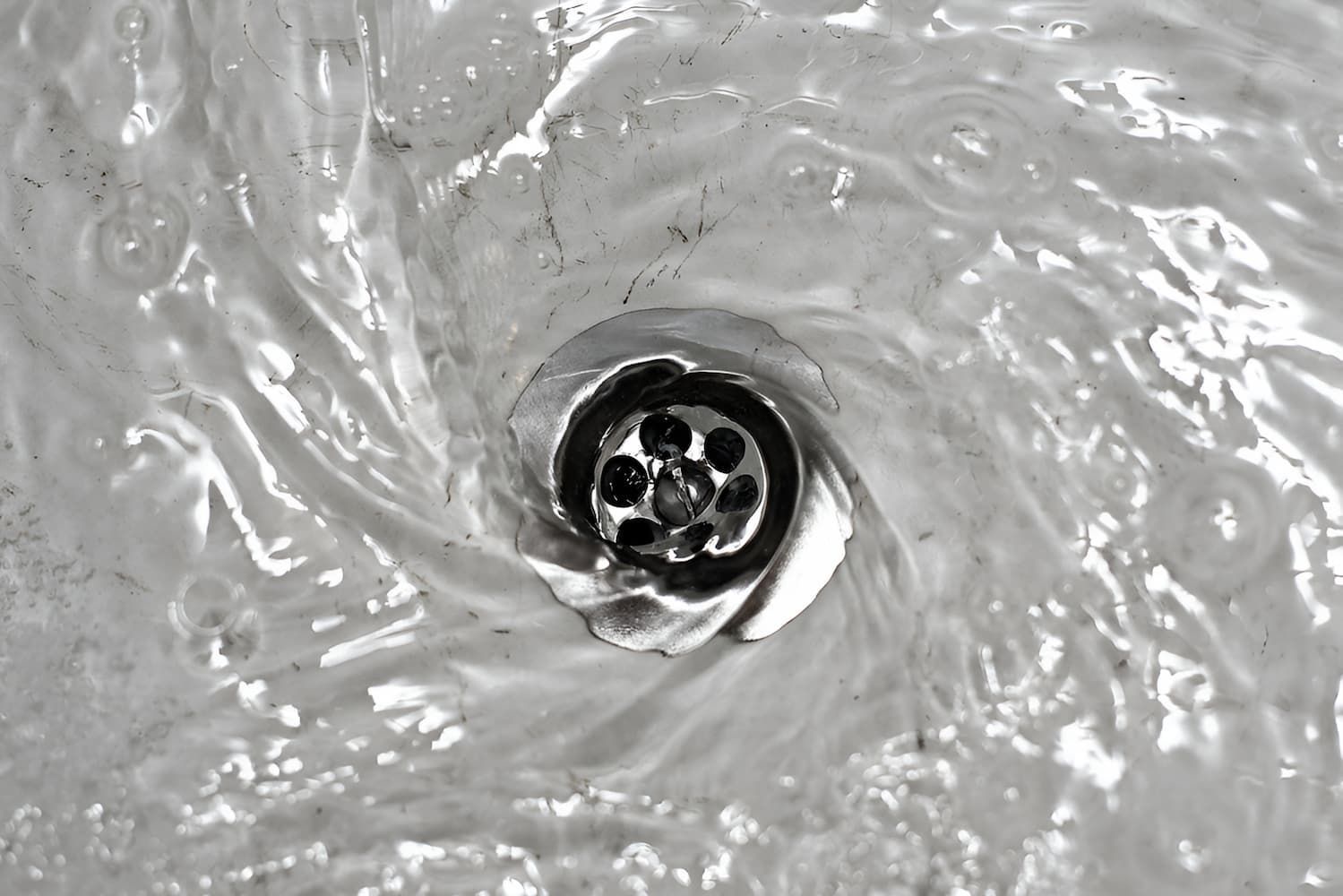 A Black And White Photo Of Water Running Down A Drain — GPS Plumbing, Drainage & Gasfitting In Dubbo, NSW